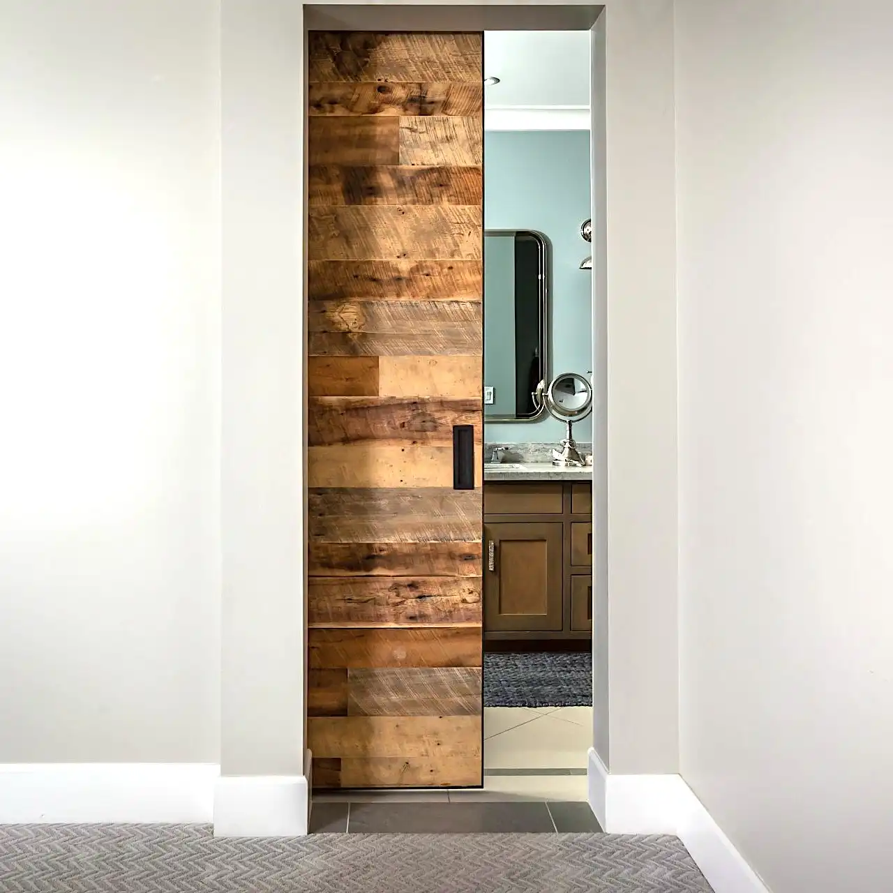  Une porte de grange en bois dans une salle de bains avec miroir. 