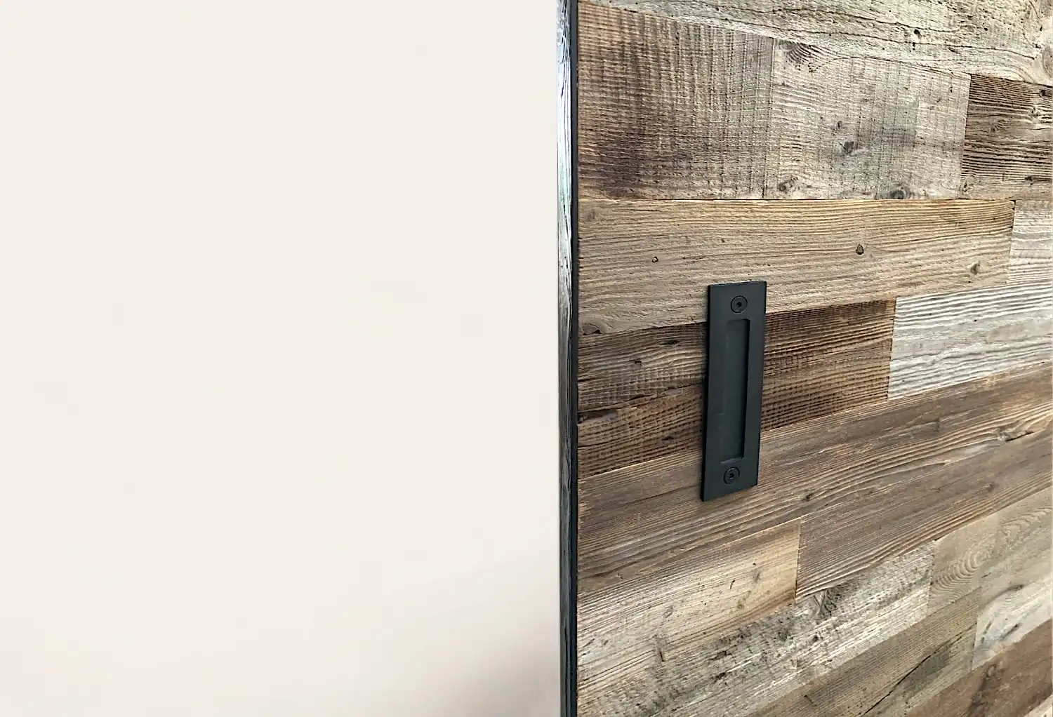 Un gros plan d'une porte coulissante en bois vieilli avec une poignée noire.