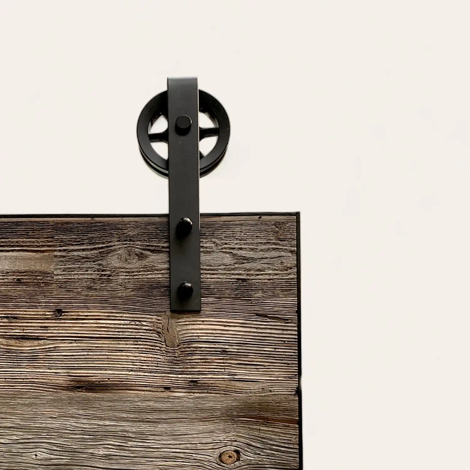 Une porte de grange en bois avec une roue noire dessus.