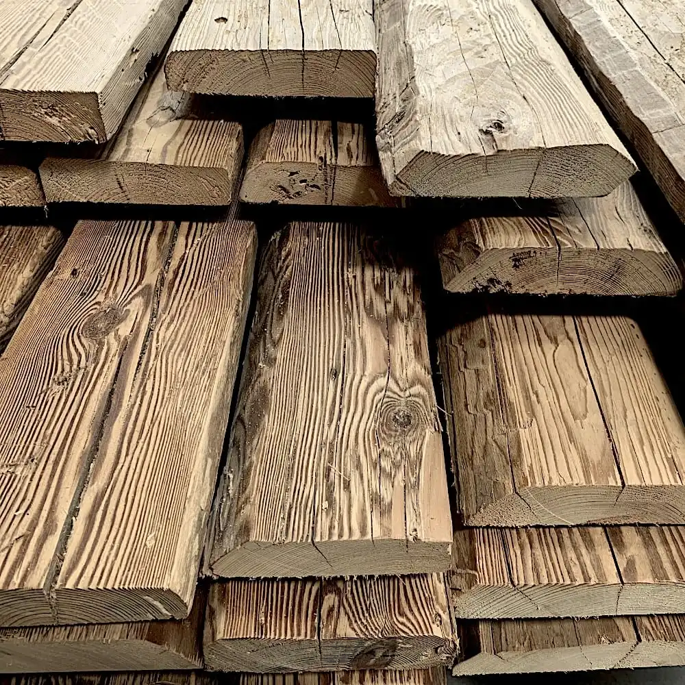  Un empilement de planches de bois grossièrement découpées, présentant le charme rustique des madriers anciens, chacune avec des textures et des nuances variées. 