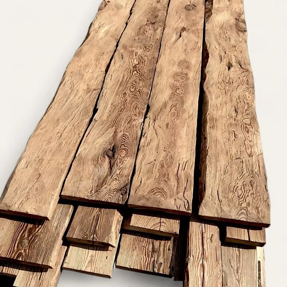  Plusieurs longues planches irrégulières en bois de vieux sapin à la texture rugueuse et naturelle empilées les unes sur les autres sur un fond uni. 