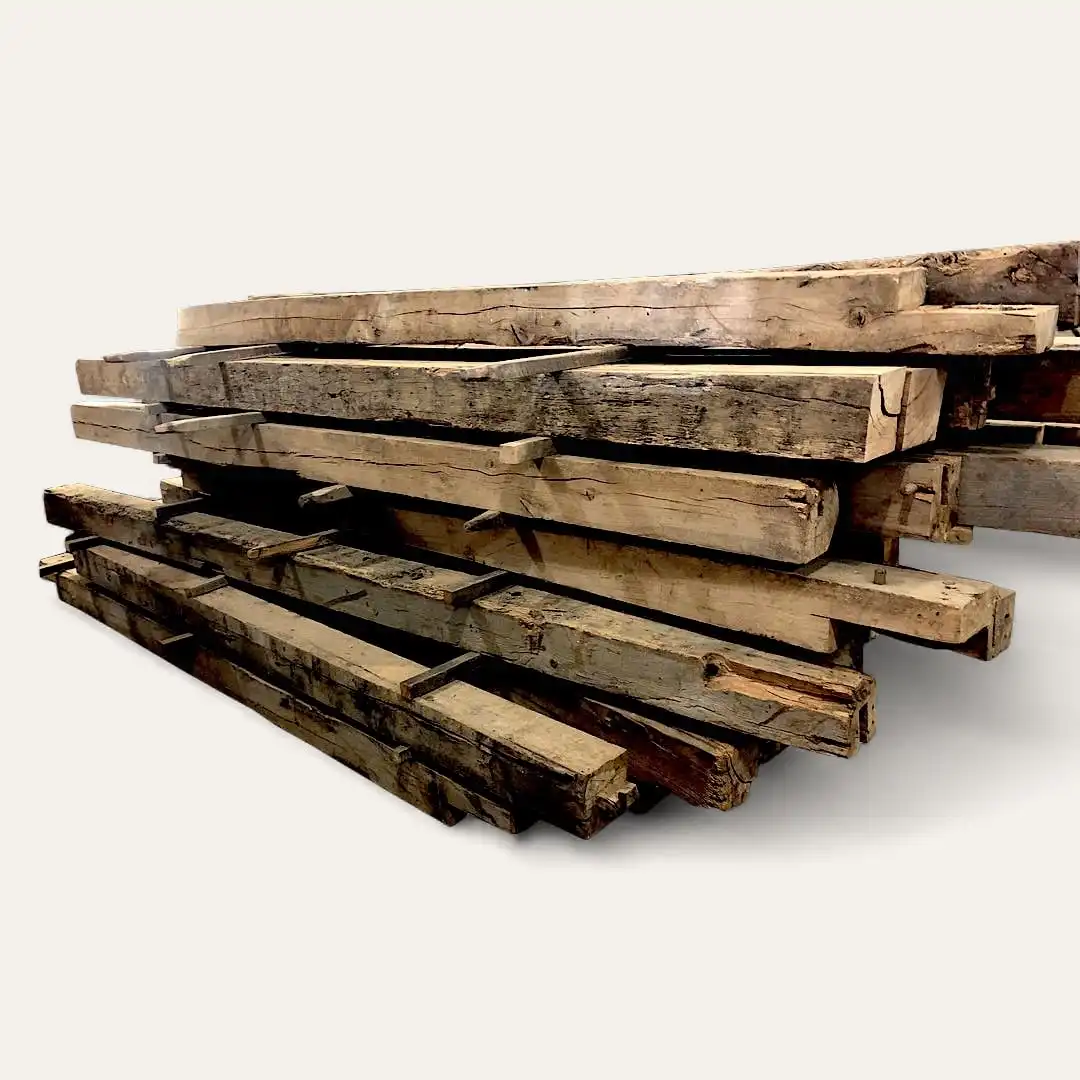  Un empilement de grandes poutres en bois patinées, constituées de poutres anciennes de récupération, disposées horizontalement. 