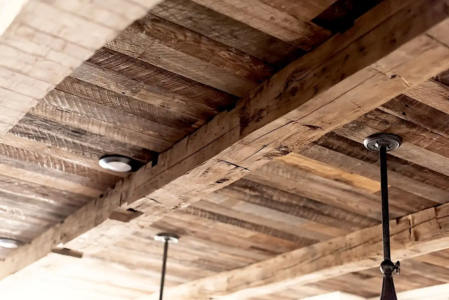 Plafond à poutres apparentes en bois avec éclairage encastré et luminaires suspendus suspendus, mettant en vedette de belles poutres anciennes de récupération.