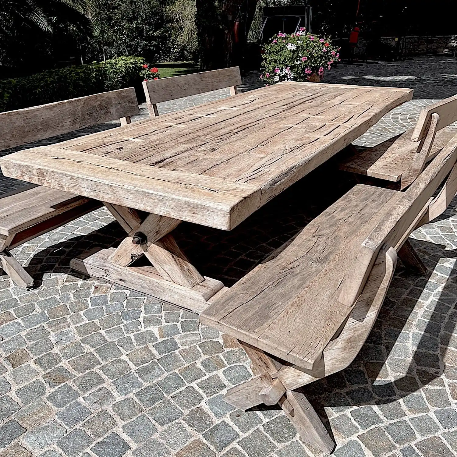  Une table de ferme et des bancs en bois rustique sur un patio pavé. 