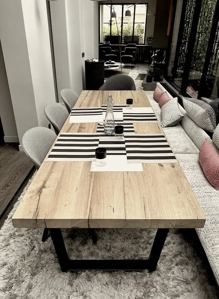 Une table rustique avec un plateau en chêne massif, reposant sur des pieds en métal noir. 