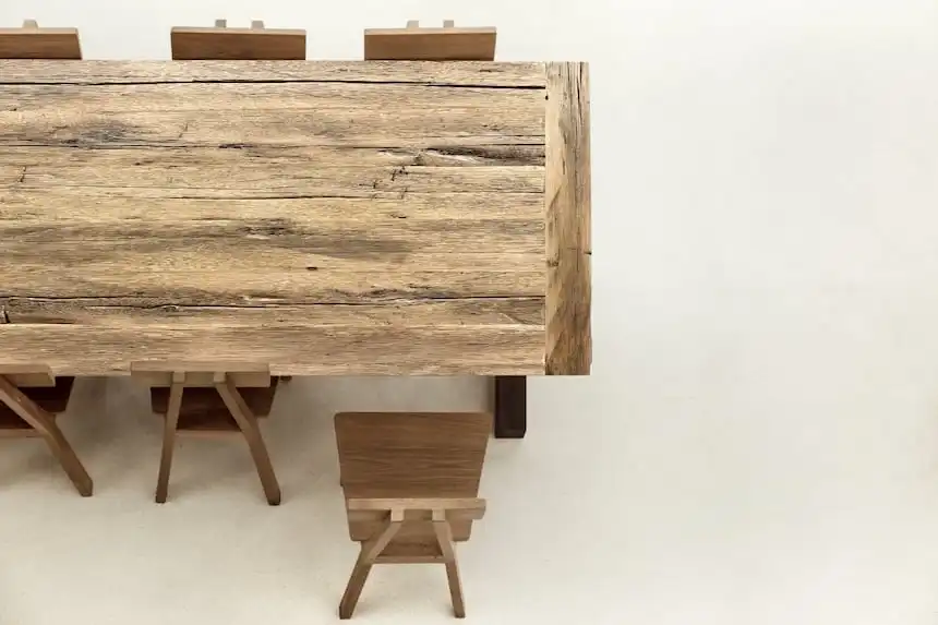 Table de ferme en bois vieilli avec texture rugueuse et rainures naturelles, entourée de chaises en bois de style simple