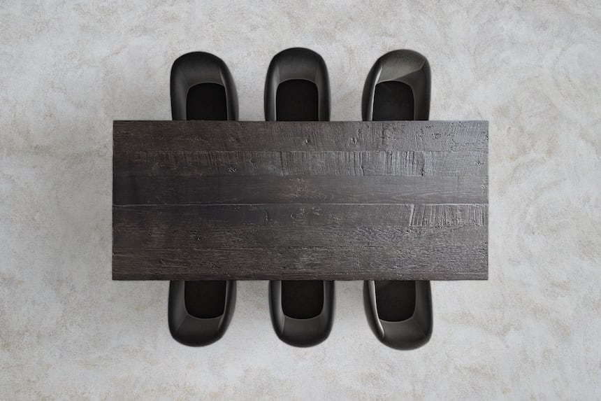Table à manger rectangulaire noir et bois avec six chaises en cuir caramel vue de dessus sur fond gris.