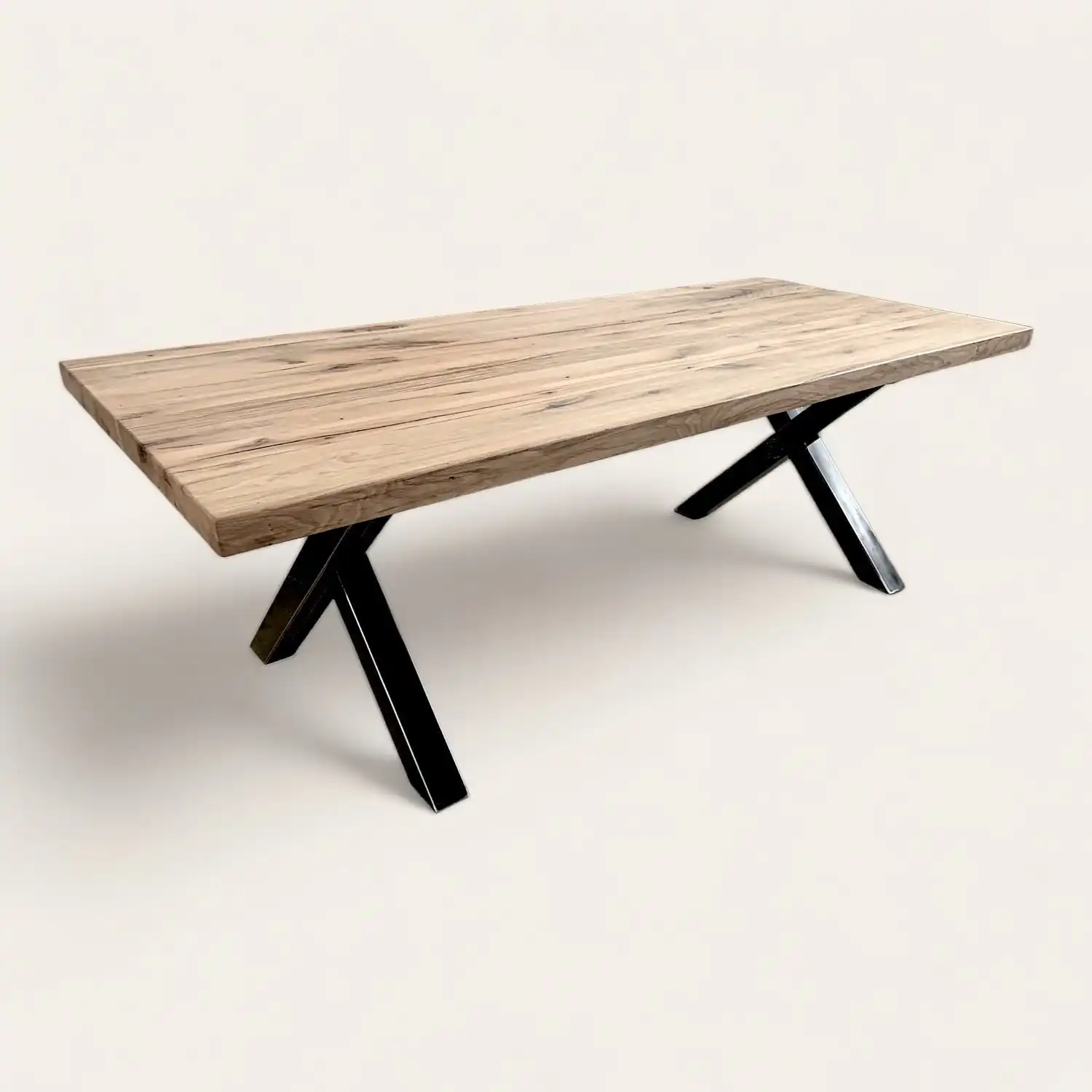  Table de salle à manger en bois vieilli avec pieds croisés en métal noir, combinant esthétique rustique et design contemporain. 