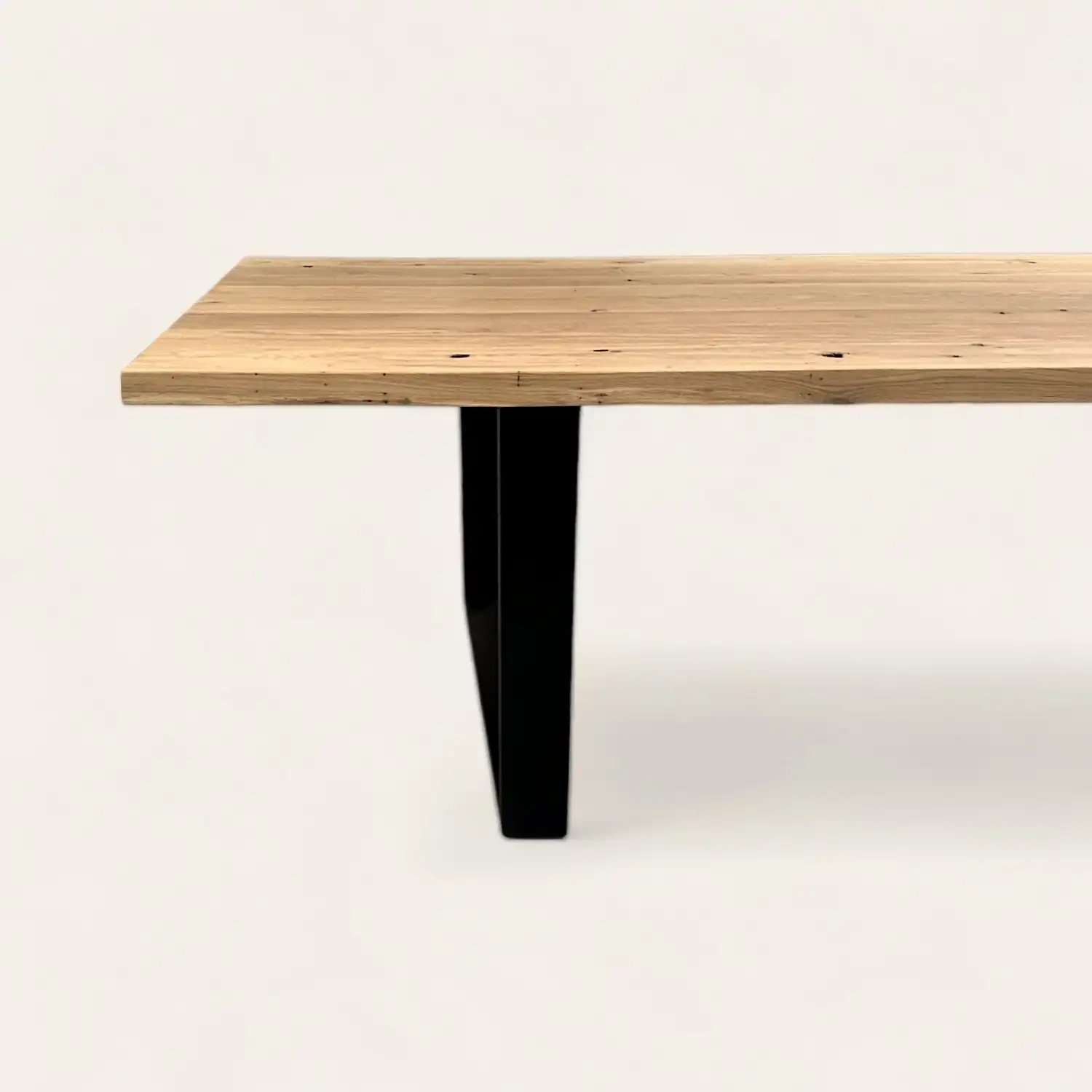  Table en bois clair ancien avec pied central en forme de T noir, conjuguant charme rustique et touche contemporaine. 