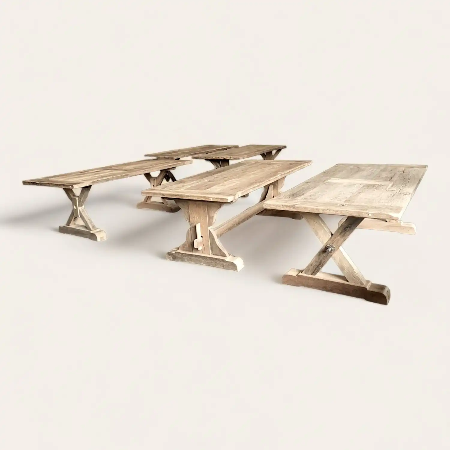  Ensemble de tables de pique-nique rustiques en bois ancien patiné avec bancs intégrés, évoquant un style champêtre et convivial, idéal pour des repas en extérieur ou dans un cadre familial traditionnel. 