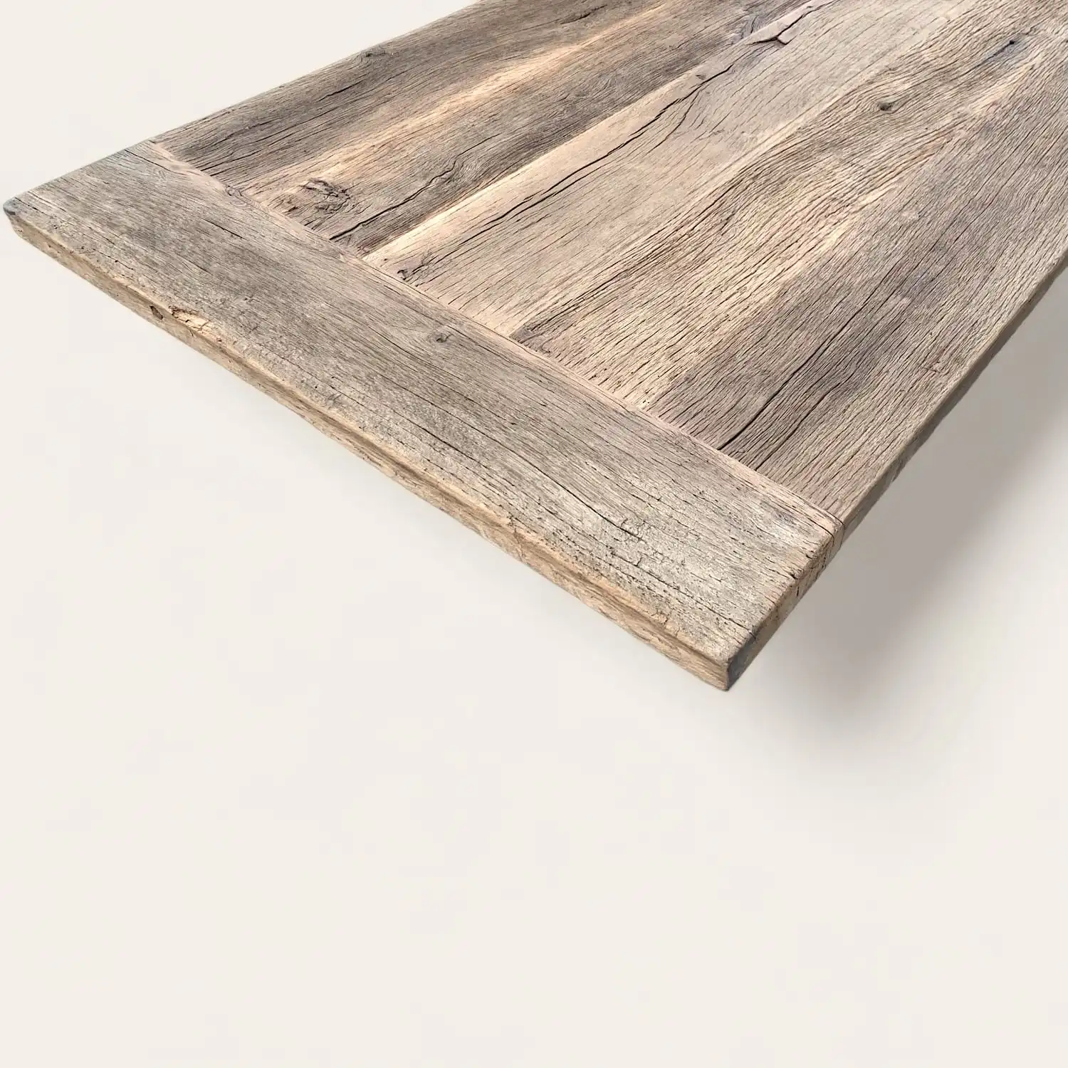  Vue en angle sur le plateau d'une table en bois ancien rustique, mettant en valeur la patine naturelle et les textures riches du bois, idéal pour un intérieur au design authentique et durable. 