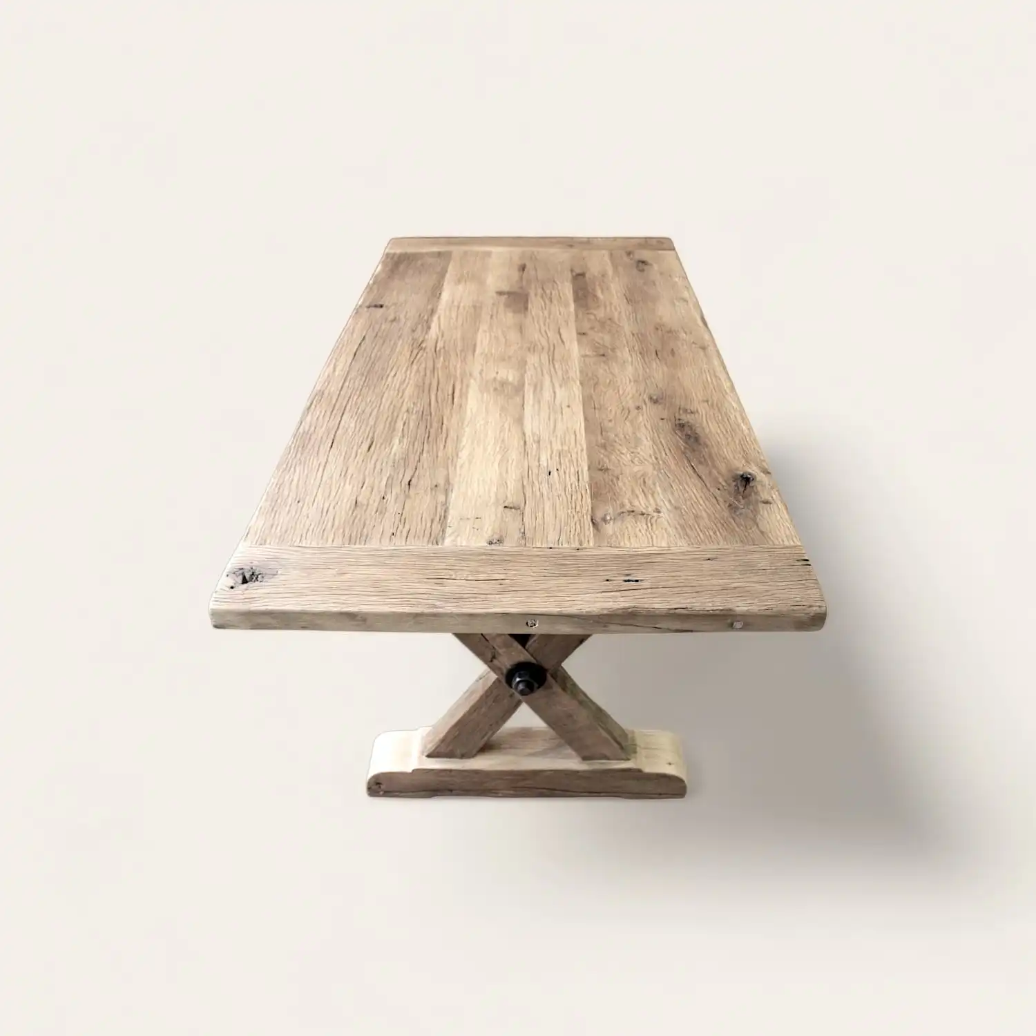  Vue en perspective d'une table rustique robuste en bois ancien avec base centrale en croix, offrant une esthétique durable et élégante pour un intérieur au style authentique. 