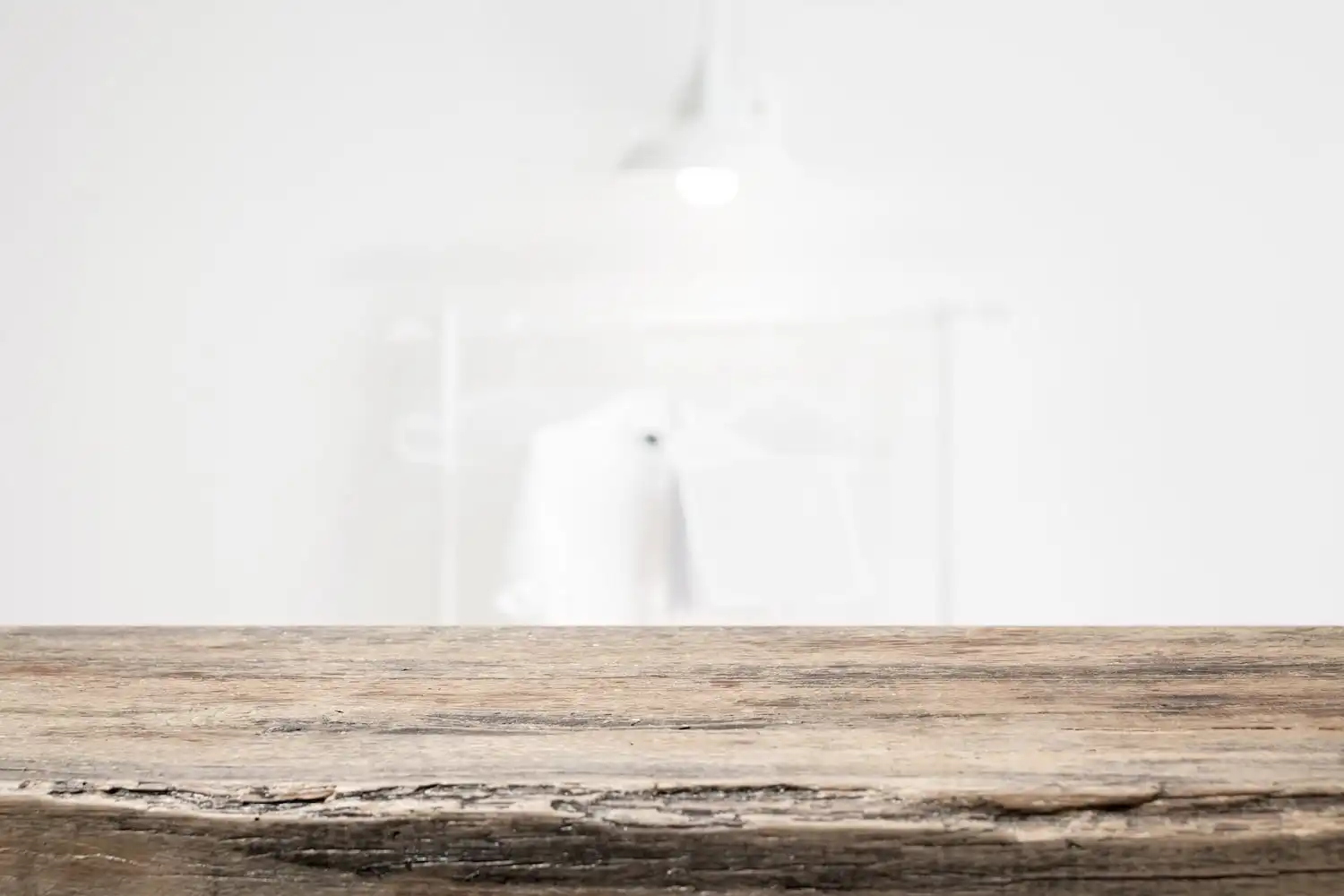 Vue de profil d'une table en bois rustique robuste sur un fond flou et épuré, mettant l'accent sur la texture grossière et les détails du bois ancien, évoquant la durabilité et l'artisanat de qualité.