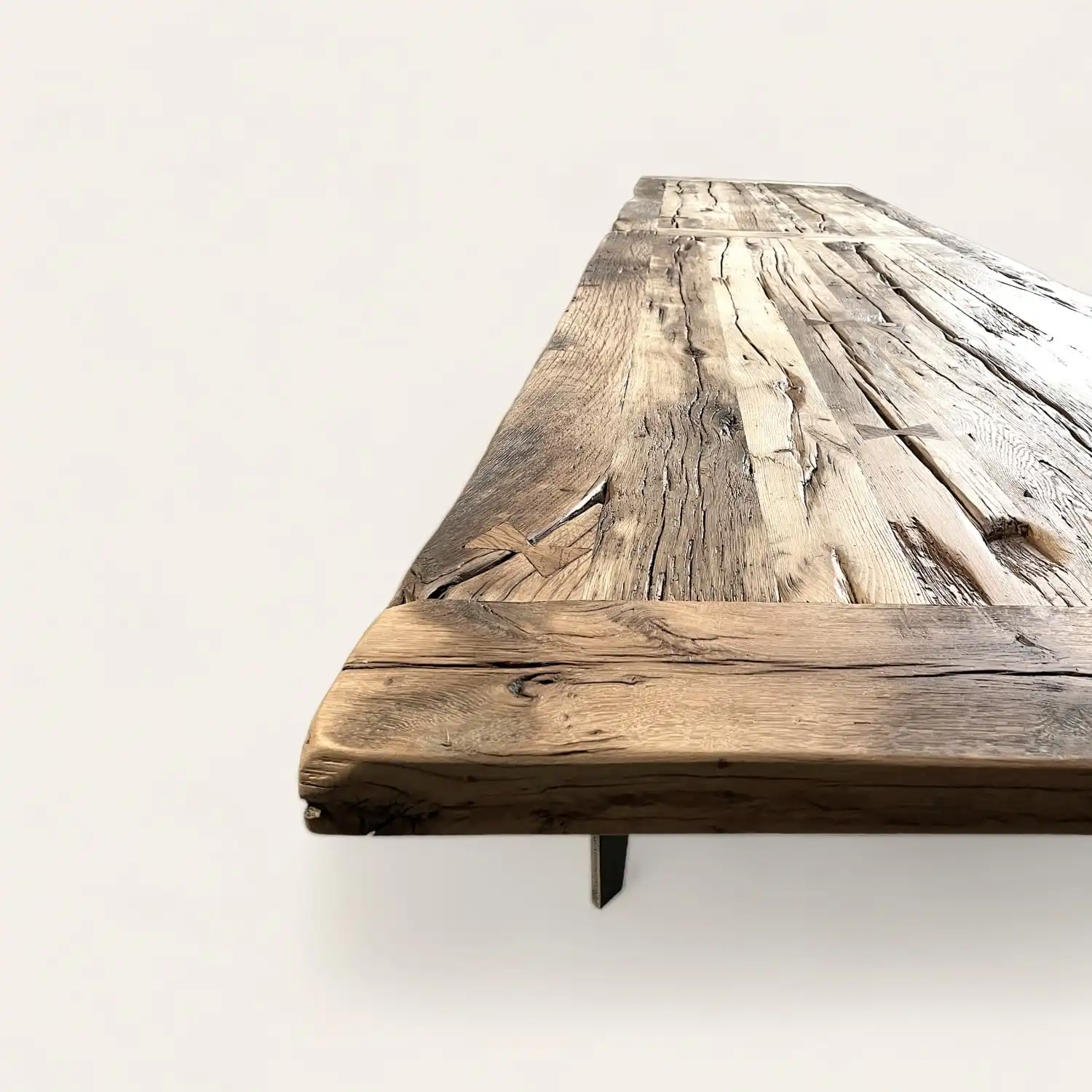  Table de fermette en bois massif avec finition naturelle vieillie, angle montrant les détails des veines et textures du bois. 