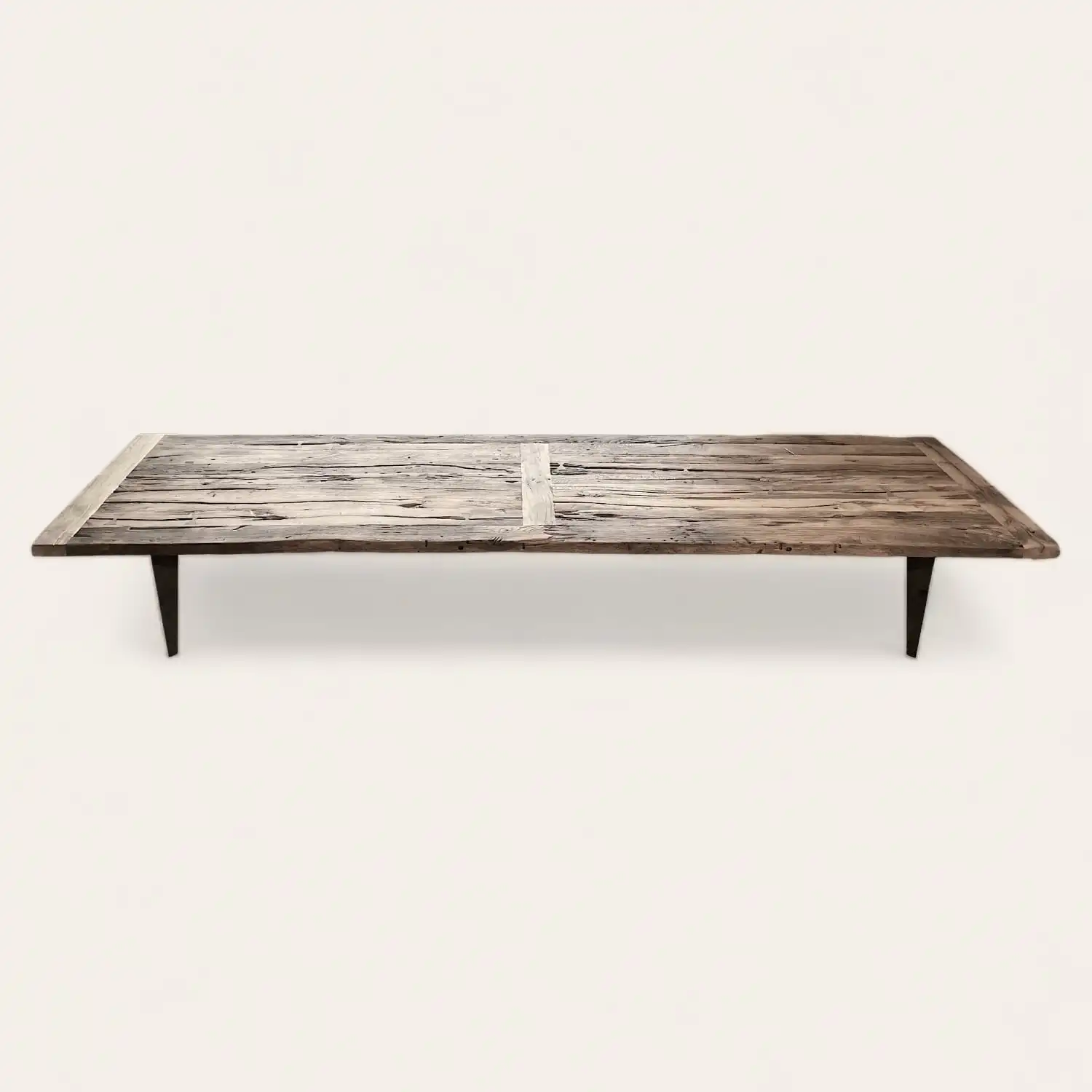  Longue table de style fermette en bois récupéré avec des jambes fines, affichant une patine naturellement vieillie et des détails rustiques. 
