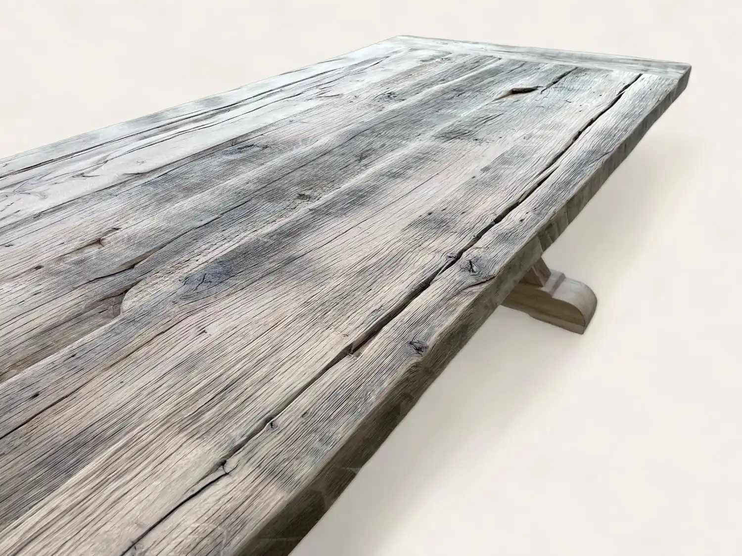 Vue rapprochée d'une table de ferme rustique avec une surface patinée et des motifs de grain de bois visibles.