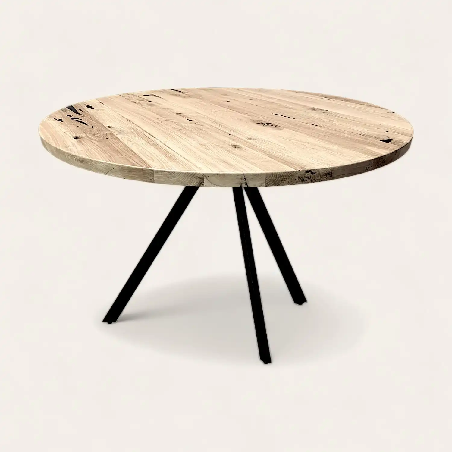  Une table ronde en vieux bois avec des pieds noirs sur fond blanc. 