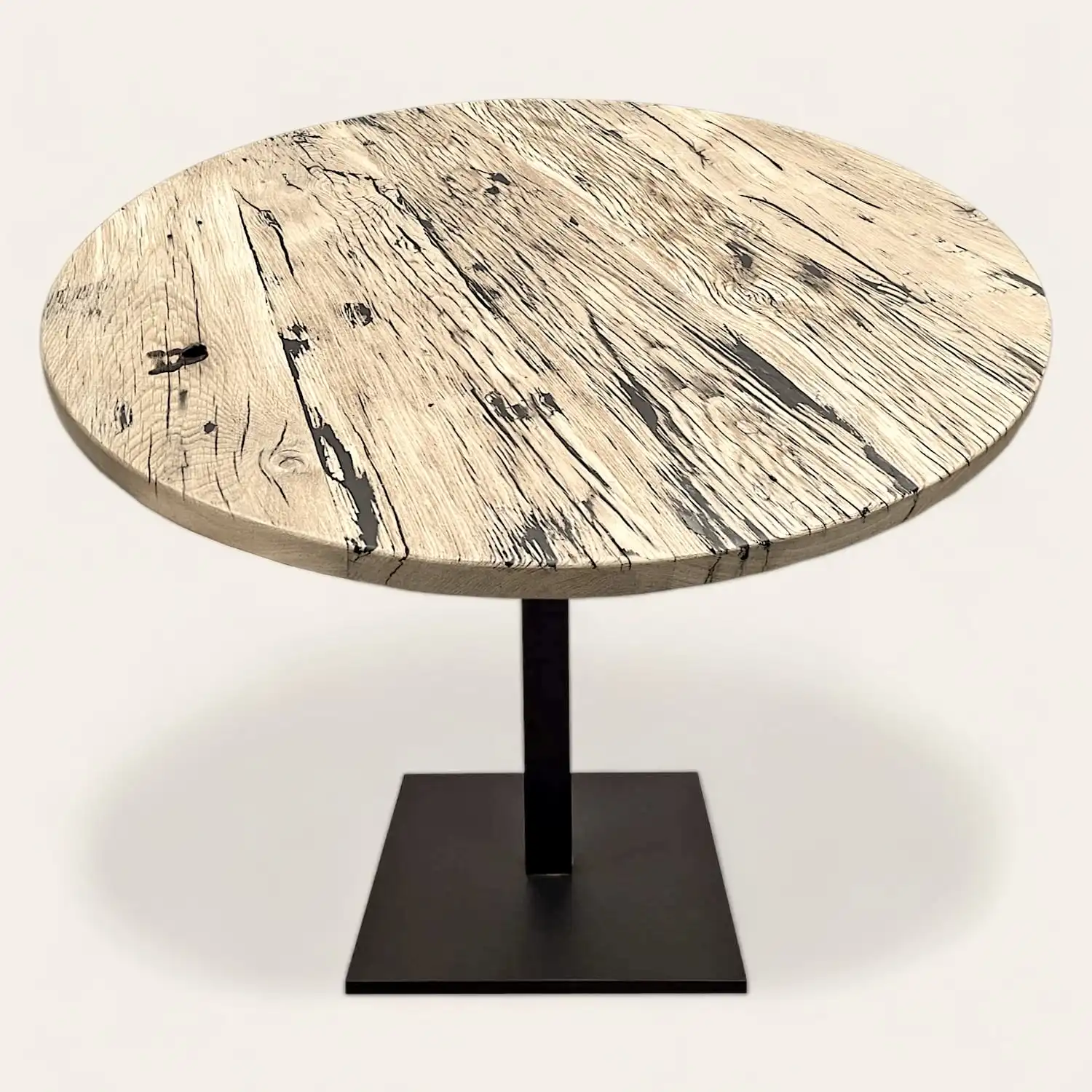  Une table ronde en bois de wagon avec un piètement noir. 