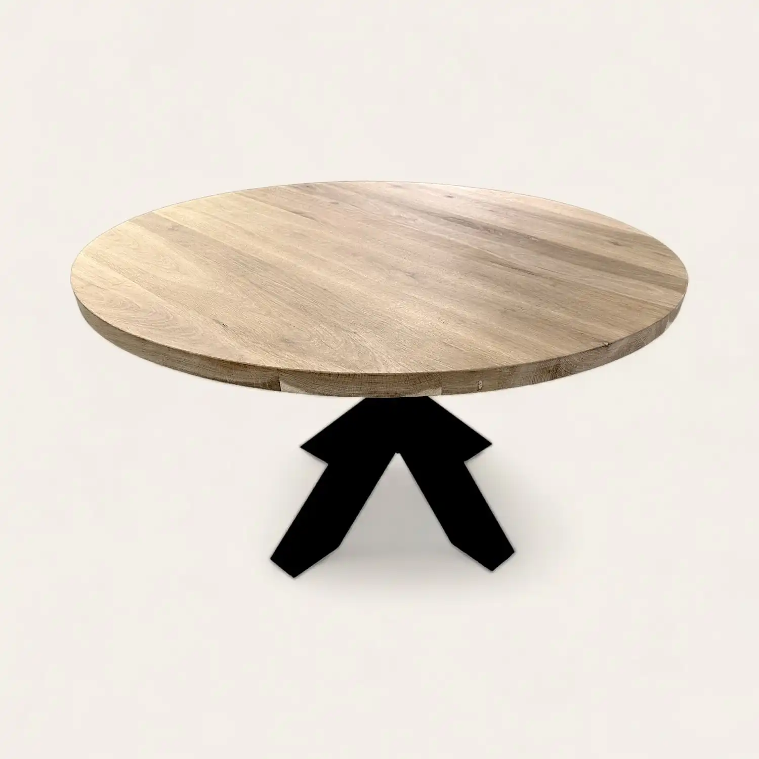  Une table ronde en vieux bois avec des pieds noirs sur fond blanc. 