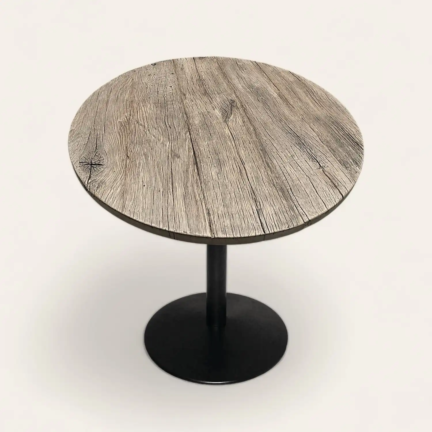  Une table ronde en bois rustique avec un piètement noir. 