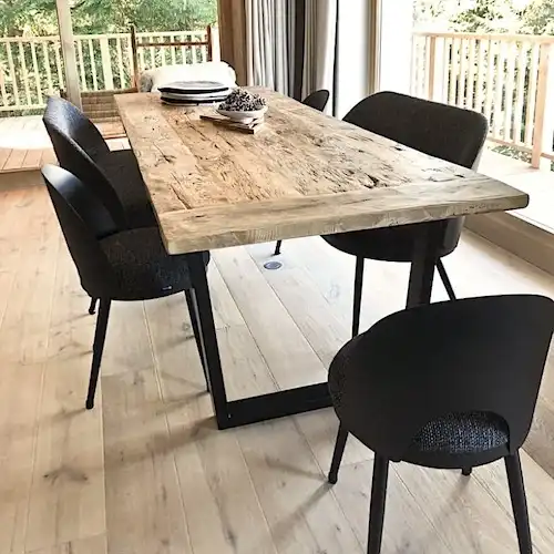 Une table à manger rustique avec des chaises noires et un parquet.