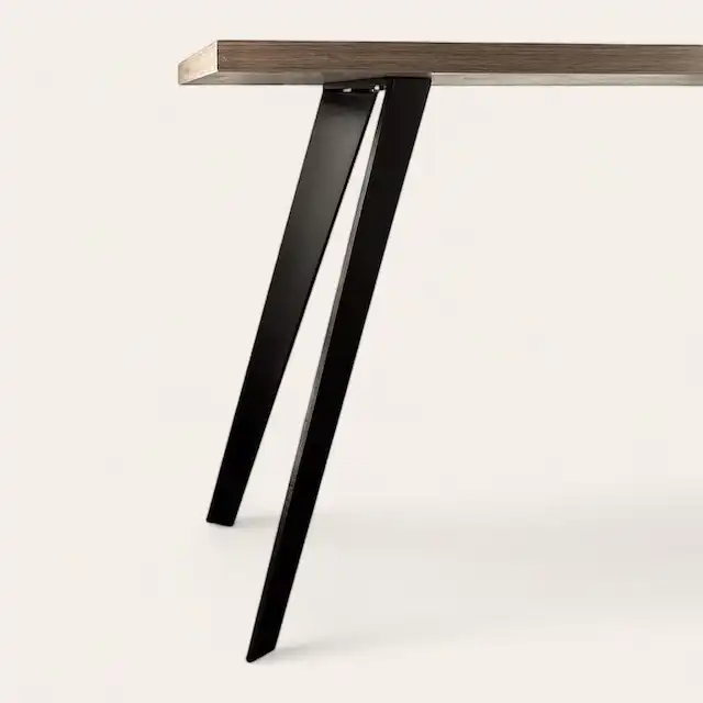  Vue rapprochée d'une table moderne avec un plateau en bois et des pieds en métal inclinés. 