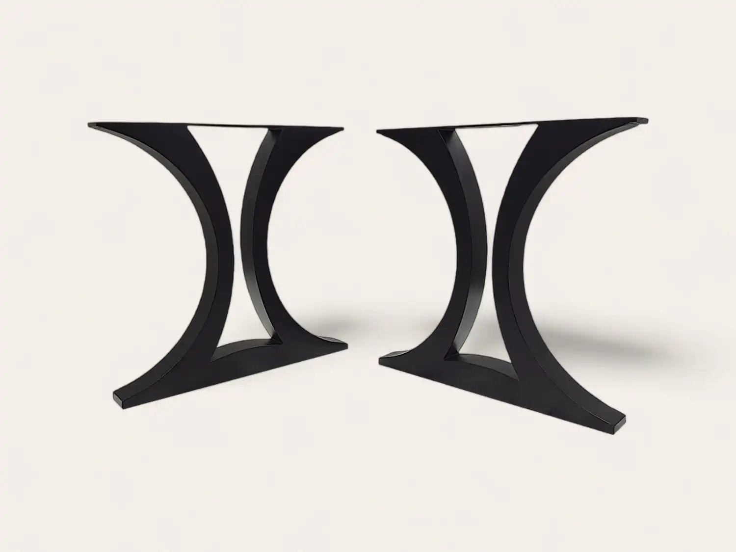 Paire de pieds de table noirs et courbés au design moderne sur fond blanc.