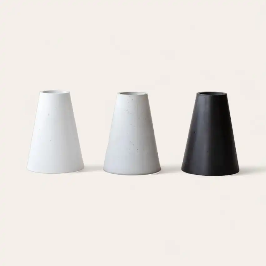  Trois pieds géométriques en céramique dans des tons allant du blanc au noir, présentés sur un fond neutre. 