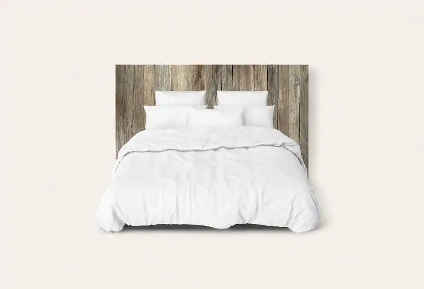 Un lit avec une literie blanche contre une tête de lit rustique en bois.