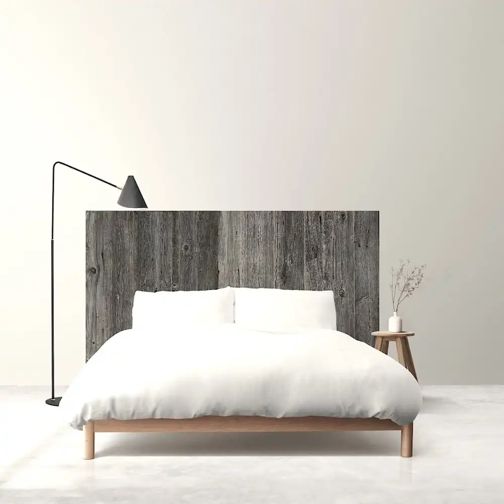  Une chambre minimaliste avec un cadre de lit en bois, une literie blanche et une tête de lit rustique, accompagnée d'un lampadaire et d'une petite table d'appoint avec un vase. 