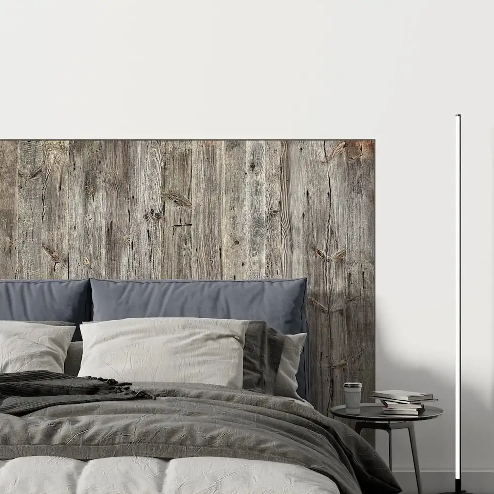  Une chambre moderne avec une tête de lit rustique en bois et un lit soigneusement fait avec une literie grise et blanche. 