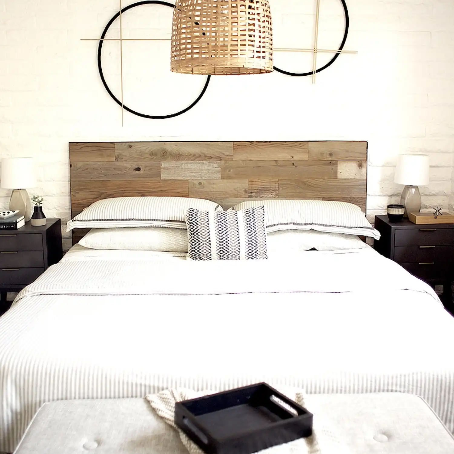  Intérieur de chambre moderne avec tête de lit rustique en bois, literie blanche et tables de chevet symétriques. 