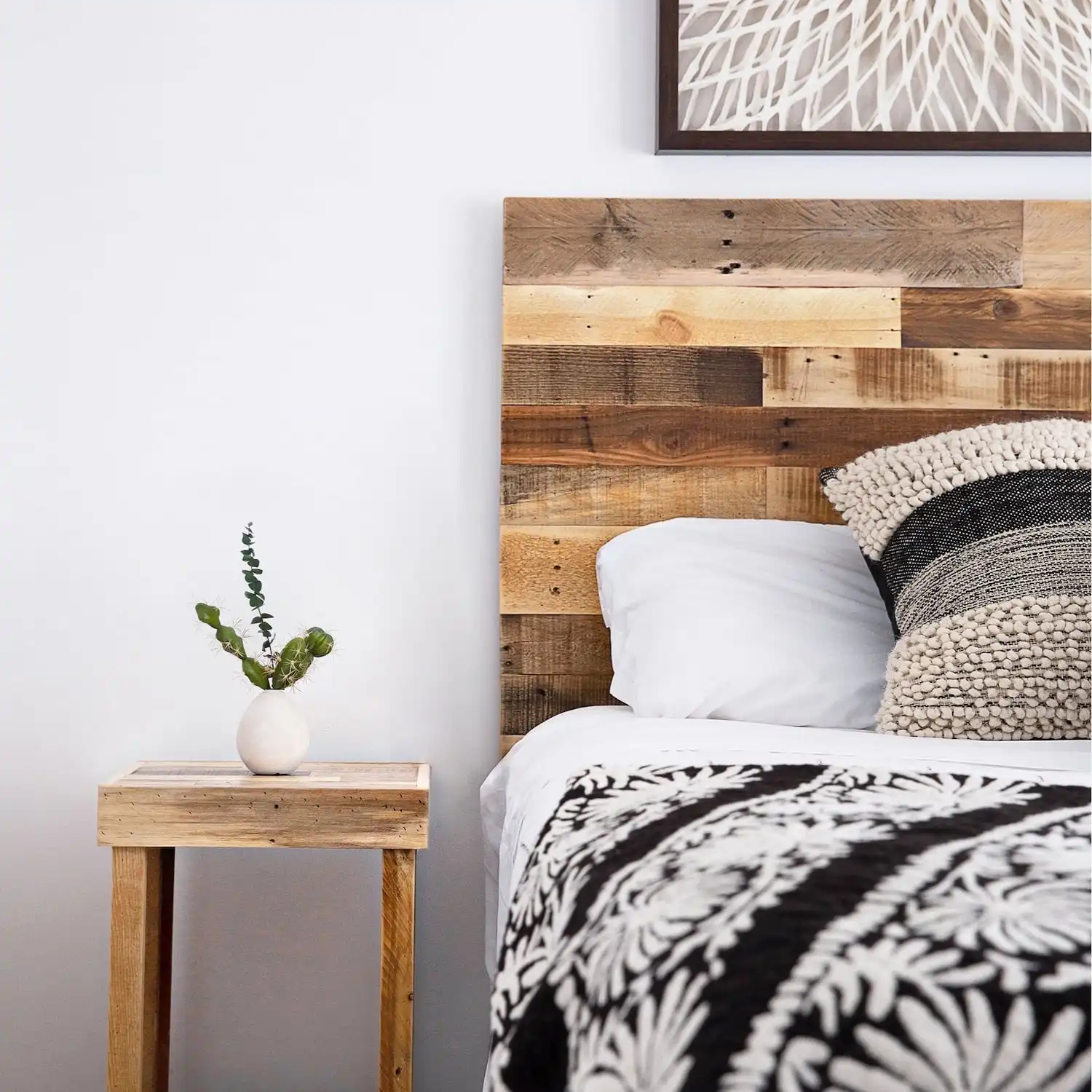  Un coin chambre douillet avec une tête de lit en bois ancien, une literie à motifs et une petite table de nuit avec une plante. 
