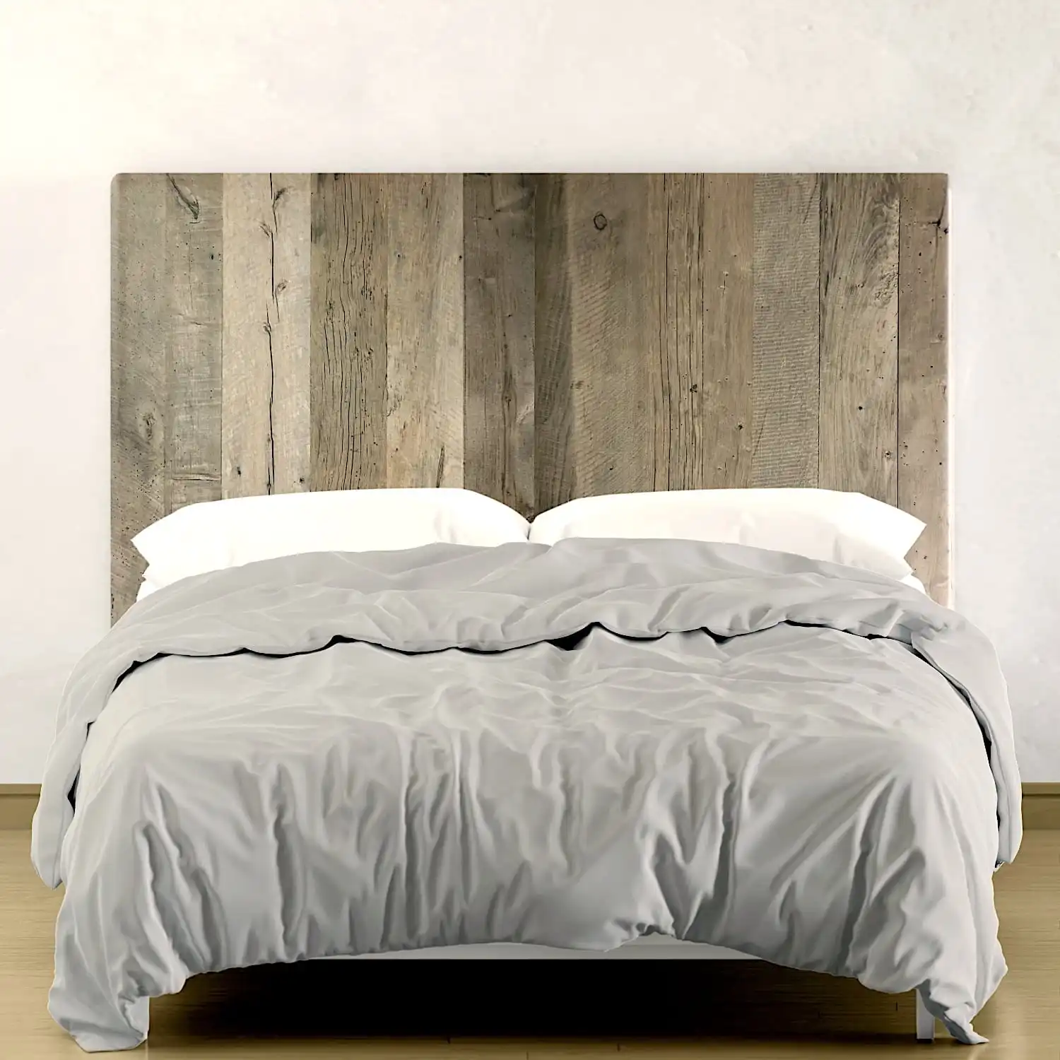  Un lit avec une literie grise et une tête de lit rustique en bois contre un mur de couleur claire. 