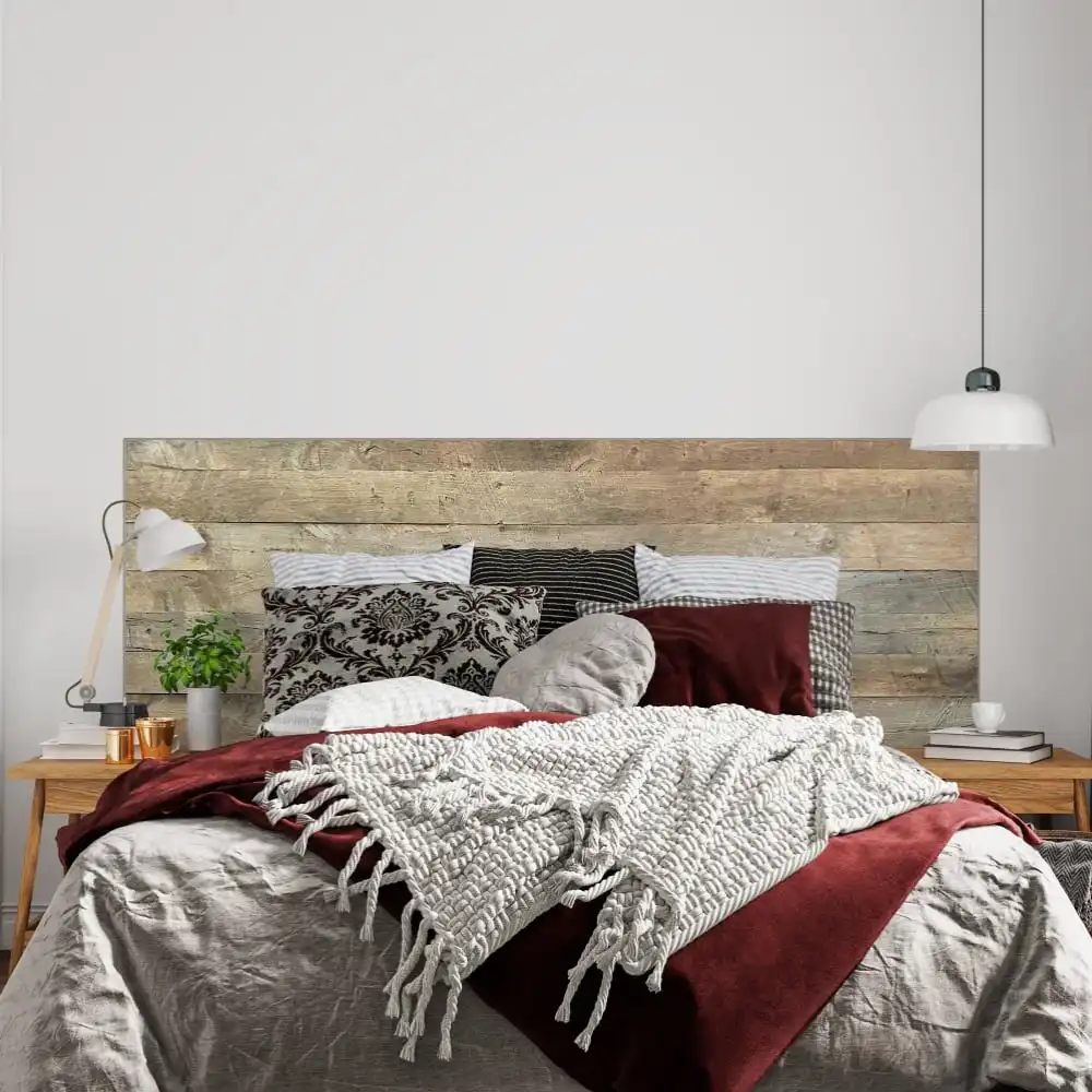  Une chambre moderne et confortable avec une tête de lit en bois de grange vieilli, des murs blancs et un lit orné d'un jeté en grosse maille et d'une literie bordeaux. 