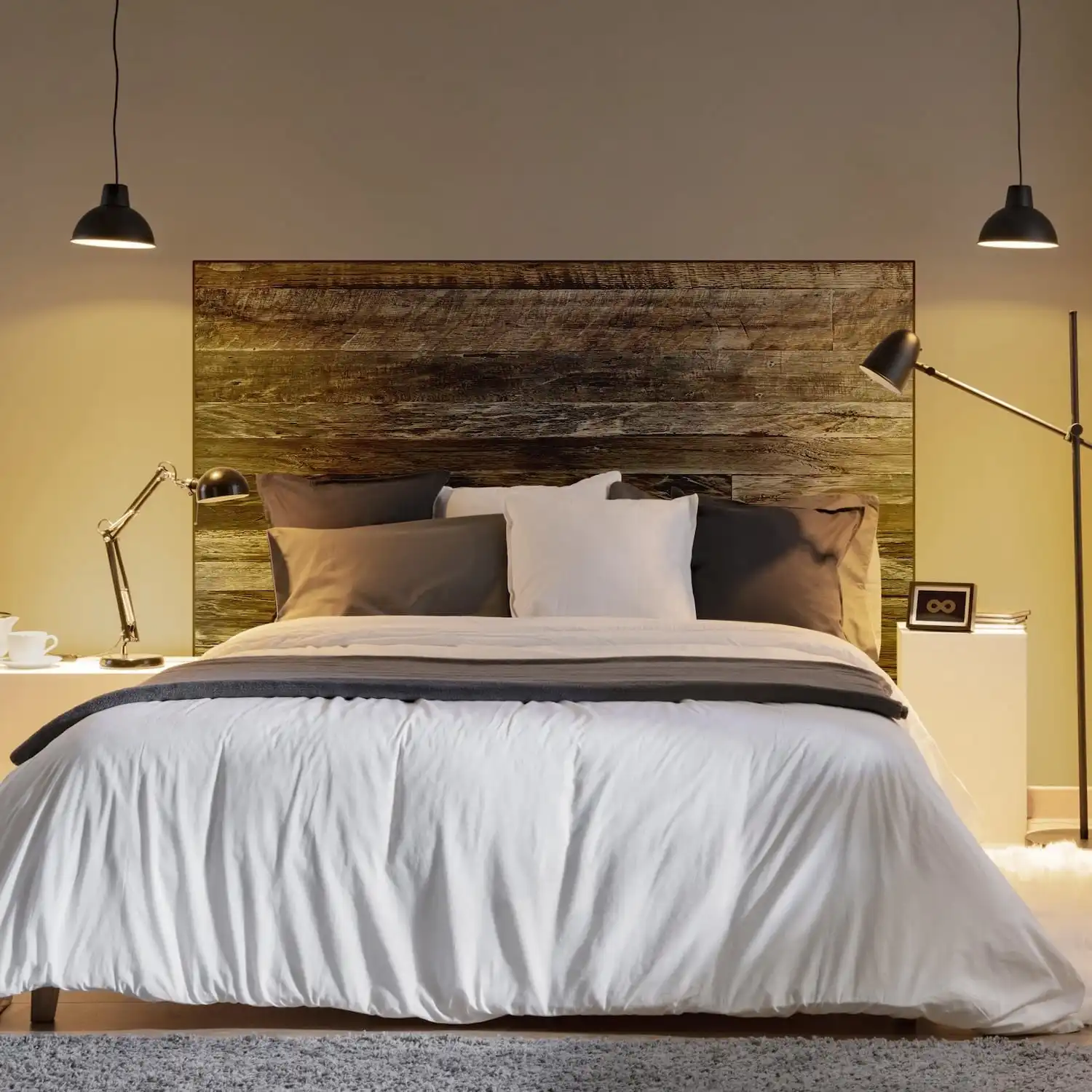  Une chambre moderne comprenant un grand lit avec une literie blanche et grise, deux suspensions suspendues et une tête de lit en bois ancien. 